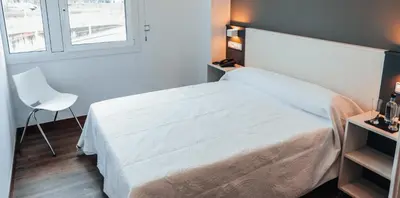a bedroom with a white bed and a white chair at Pensión Rúa Peregrino in Sarria