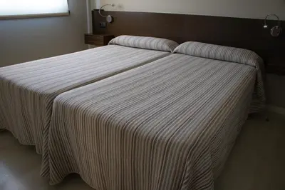 a bed with a striped blanket on top of it at PENSIÓN RESTAURANTE 