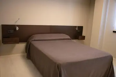 a bedroom with a bed with a brown blanket at PENSIÓN RESTAURANTE 