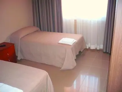 a hotel room with two beds and a window at Pensión Bos in Bergondo