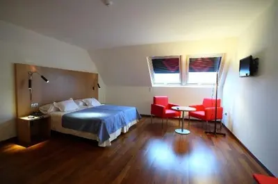 a bedroom with a bed and two red chairs at Hotel Ril in Burela de Cabo