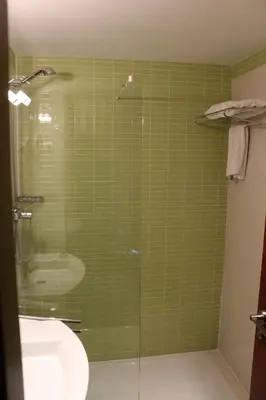 a green tiled bathroom with a shower and a sink at Hotel Ril in Burela de Cabo