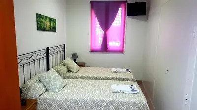 two beds in a room with a pink window at Apartamento Study 1 Select Real Caldas de Reis in Caldas de Reis