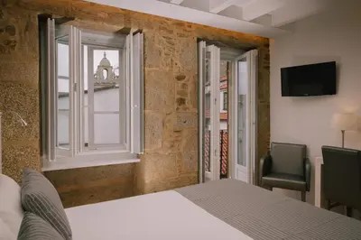 a bedroom with a bed and a window and a chair at Os Sobriños Do Pai in Santiago de Compostela