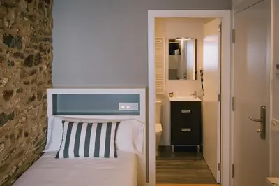a small bedroom with a bed and a mirror at Os Sobriños Do Pai in Santiago de Compostela