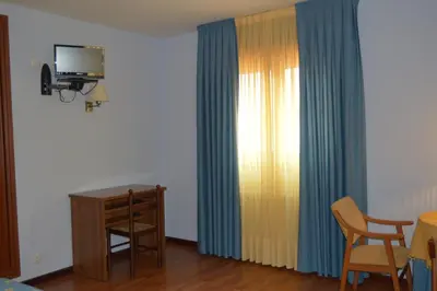 a room with a desk and a television and curtains at Hotel Restaurante Val in Antas de Ulla