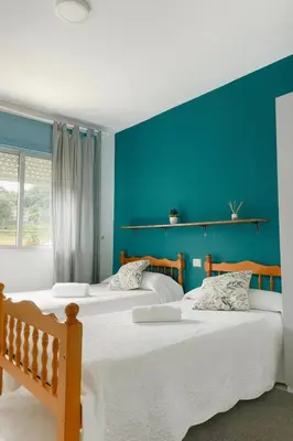 two beds in a room with a blue wall at A Senda in Caldas de Reis