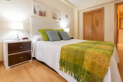 a bedroom with a large bed and a night stand at Apartamento Centro Santiago in Santiago de Compostela