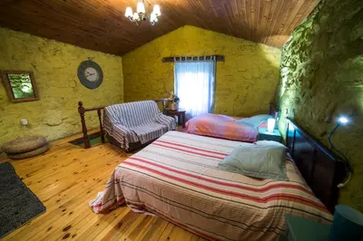 a bedroom with a bed and a chair in a room at Caserío da Castiñeira in Sas do Monte