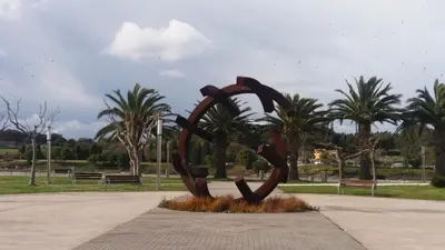 a statue in a park with palm trees in the background at Península de la paz in Lugo
