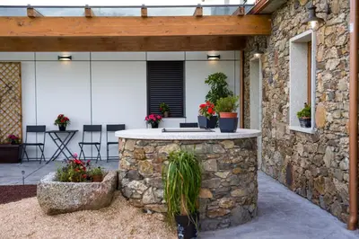 a stone walled patio with a stone counter with plants at Casa O Real in Boimorto