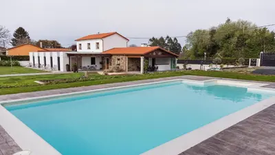 a large blue swimming pool in front of a house at Casa O Real in Boimorto