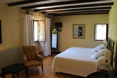 a bedroom with a white bed and a chair at Casa Grande de Soutullo in Coles