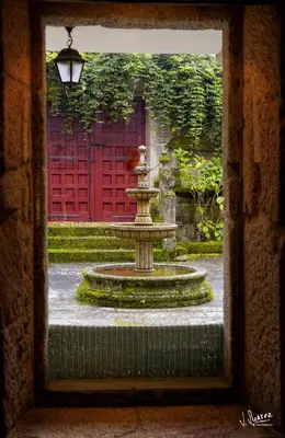 a fountain in a courtyard with a red door at Casa Grande de Soutullo in Coles