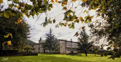 an old house on a grassy field with trees at Casa Grande de Soutullo in Coles