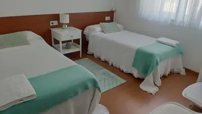 a bedroom with two beds with green and white sheets at PortoSantiago in Portomarin