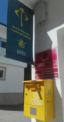 a yellow box with a sign on the side of a building at PortoSantiago in Portomarin