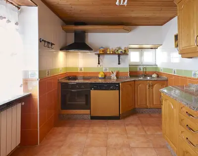 a large kitchen with wooden cabinets and a stove at Casa Samuel in Navia