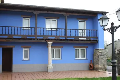 a blue house with a balcony and a street light at Casa Samuel in Navia