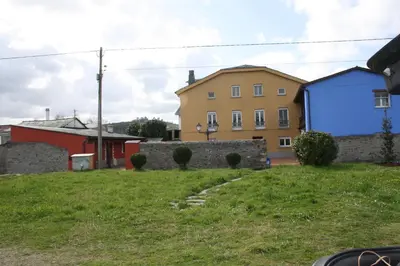 a house on a grassy hill next to a building at Casa Samuel in Navia