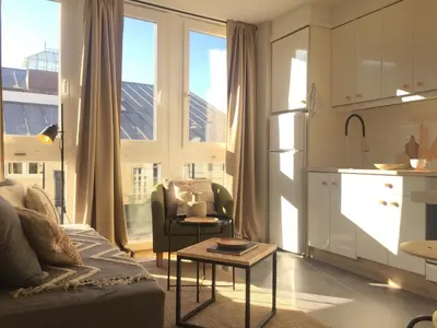 a living room with a couch and a table and a kitchen at Joya en Orense Centro in Ourense