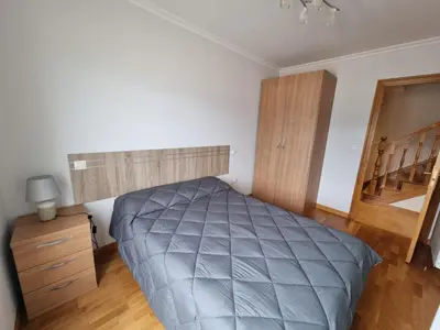 a bedroom with a large bed and a wooden floor at Dúplex 4 dormitorios en Playa Rapadoira in Foz