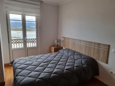 a bedroom with a bed with a view of the ocean at Dúplex 4 dormitorios en Playa Rapadoira in Foz