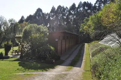 a building in a garden with trees in the background at Alvarella in Villarmayor