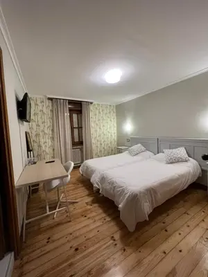 a hotel room with two beds and a desk at Hotel Regueiro in Tox