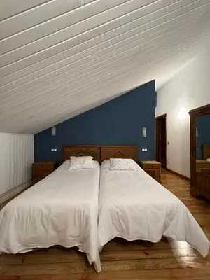 a bedroom with two beds and a blue wall at Hotel Regueiro in Tox