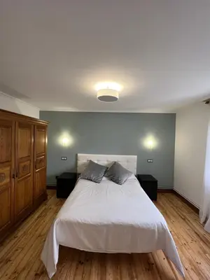a bedroom with a white bed and wooden floors at Hotel Regueiro in Tox