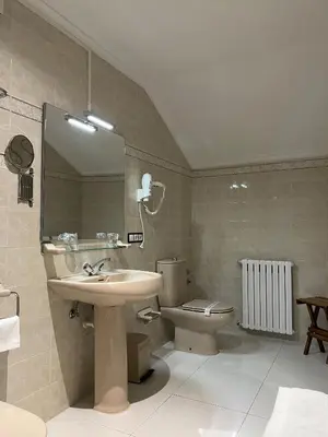 a bathroom with a sink and a toilet and a mirror at Hotel Regueiro in Tox