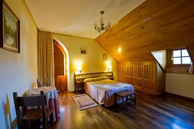 a bedroom with two beds and a wooden ceiling at Hotel Restaurante La Casilla in Cangas del Narcea