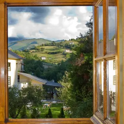 a window with a view of a field and houses at Hotel Restaurante La Casilla in Cangas del Narcea