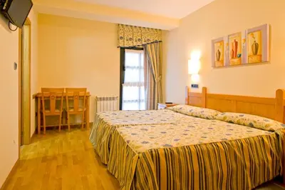 a hotel room with two beds and a window at Hotel Restaurante La Casilla in Cangas del Narcea
