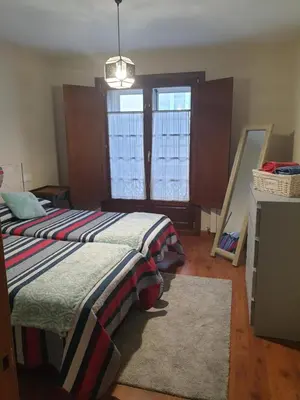 a bedroom with a bed and a dresser and windows at Apartamento Cine Colón in Ribadeo
