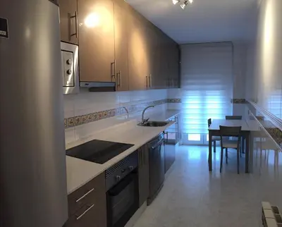 a kitchen with white cabinets and a table in it at Tres dormitorios con magníficas vistas al mar in Foz