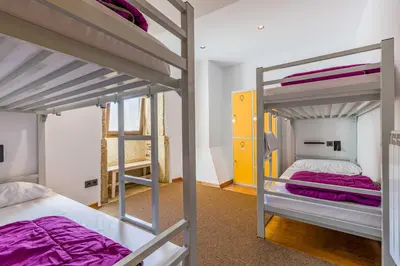 a bedroom with two bunk beds with purple sheets at Albergue O Candil in Melide
