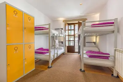 a room with three bunk beds with purple sheets at Albergue O Candil in Melide