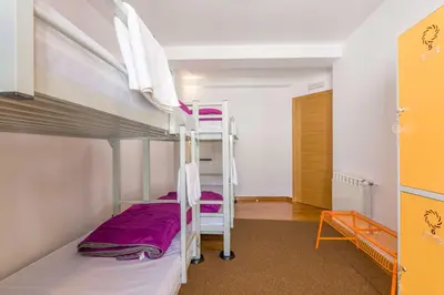 a bedroom with two bunk beds with purple sheets at Albergue O Candil in Melide