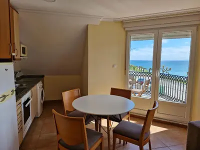 a kitchen with a table and chairs and a view of the ocean at Apartamento Foz Playa in Foz