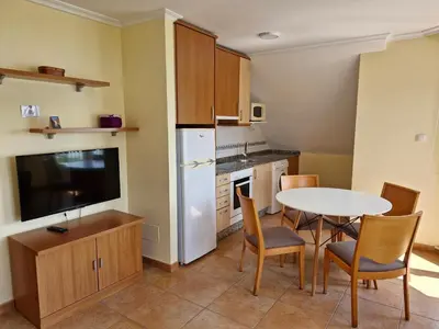 a kitchen with a white refrigerator and a table and chairs at Apartamento Foz Playa in Foz