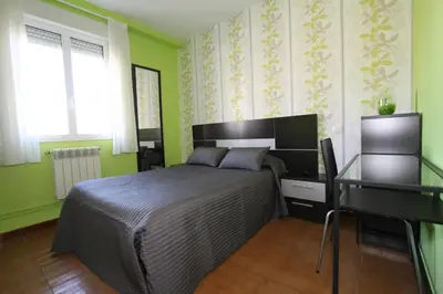 a bedroom with a bed and a desk and green walls at PR Plaza de Galicia in Santiago de Compostela