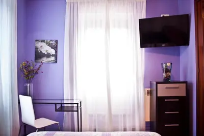 a bedroom with a purple wall with a window and a desk at PR Plaza de Galicia in Santiago de Compostela