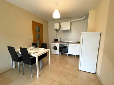 a kitchen with a table and a white refrigerator at Alojamientos Barreiros 3000 in Barreiros