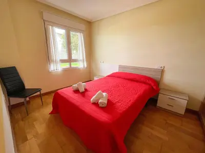 a bedroom with a red bed with two towels on it at Alojamientos Foz 3000 in Foz