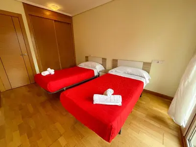 two beds with red sheets in a room at Alojamientos Foz 3000 in Foz