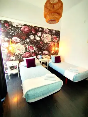 three beds in a room with a floral wall at Hostal Mafer in Santiago de Compostela