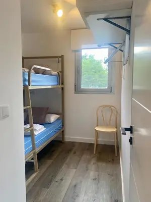 a room with bunk beds and a chair and a window at Casa de Campo Cruz de Pedra in Portomarin