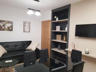 a living room with a black couch and a tv at Casa de Campo Cruz de Pedra in Portomarin